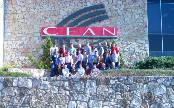 c-fan headquarters with employees standing under logo on the front of the building